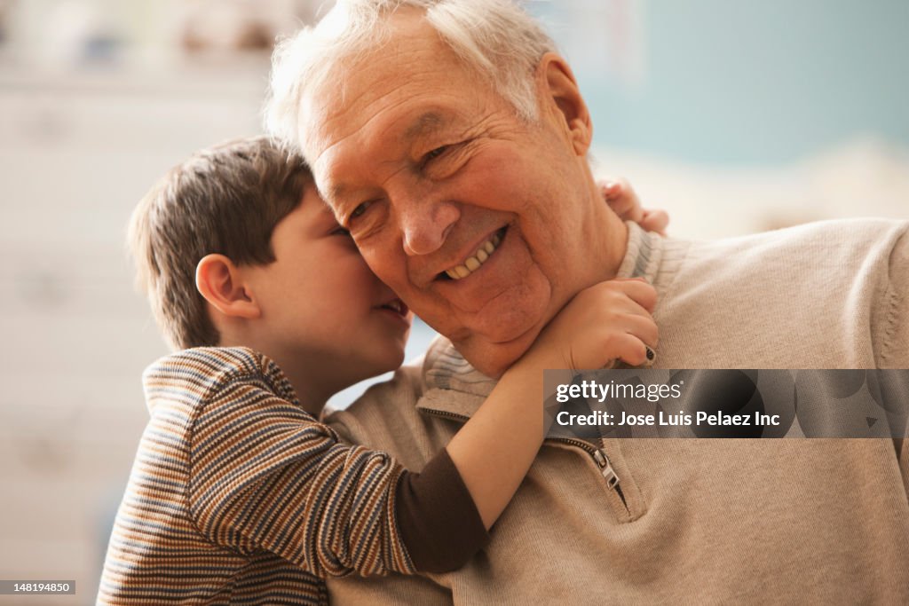 Caucasian boy telling grandfather a secret