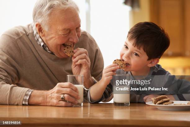 caucasian grandfather and grandson eating milk and cookies - goûter photos et images de collection