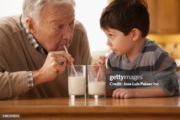 caucasian grandfather and grandson drinking milk together - milk glass stock pictures, royalty-free photos & images