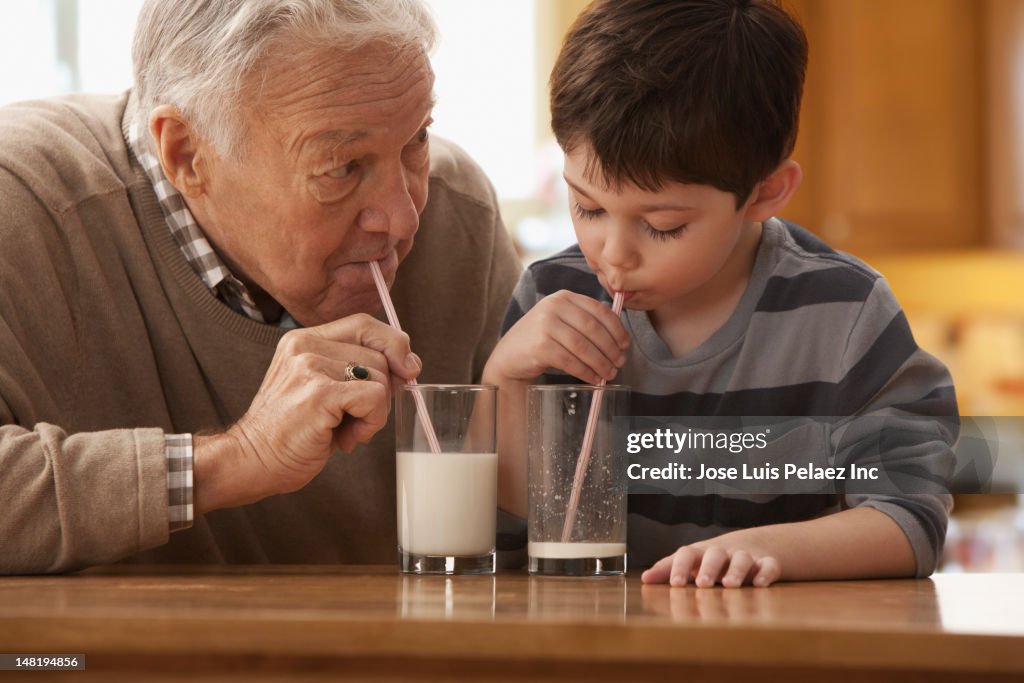 Caucasian grandfather and grandson drinking milk together