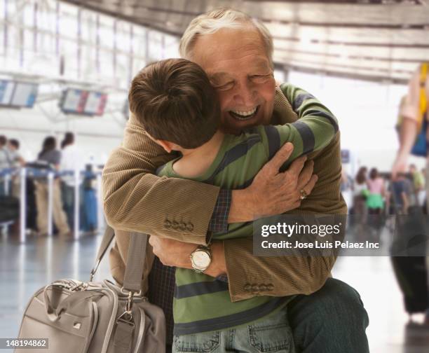 caucasian man hugging grandson in airport - hi 5 stock pictures, royalty-free photos & images