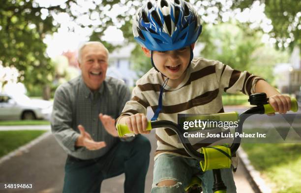 caucasian man teaching grandson to ride a bicycle - first grandchild stock pictures, royalty-free photos & images