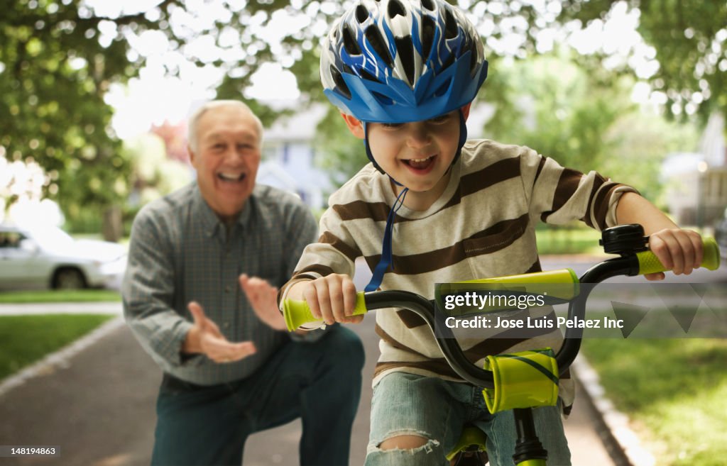 Caucasian man teaching grandson to ride a bicycle