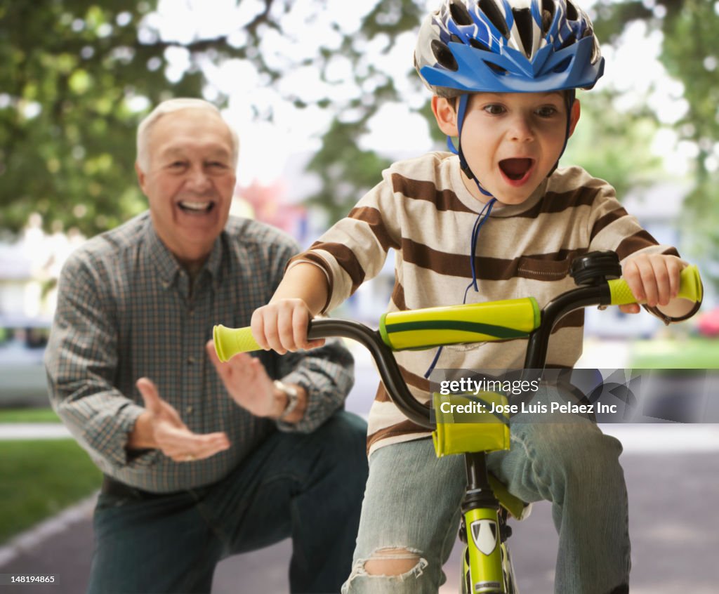 Caucasian man teaching grandson to ride a bicycle