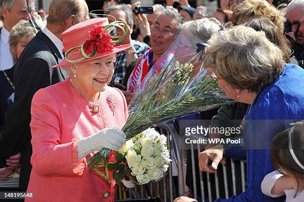 Queen Elizabeth II receives flowers from members of the public in Victoria Square during her Diamond Jubilee visit to the City on July 12, 2012 in...