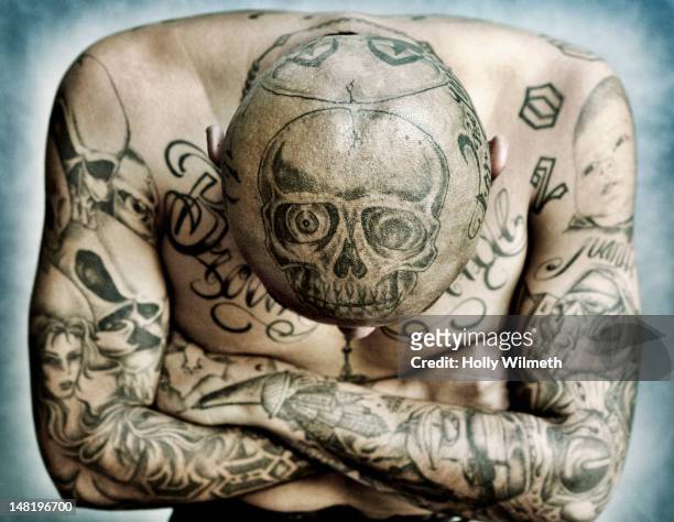 hispanic man covered in tattoos - skull tattoos stock-fotos und bilder