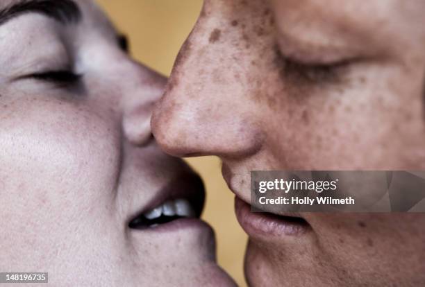 close up of caucasian lesbians kissing - kussen stockfoto's en -beelden