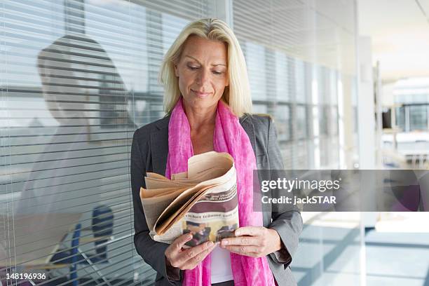 businesswoman reading periódico - bien vestido fotografías e imágenes de stock