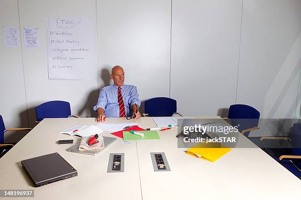 businessman sitting at conference desk - staples office stockfoto's en -beelden