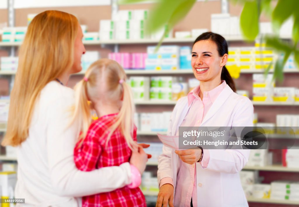 Pharmacist giving prescription to mother