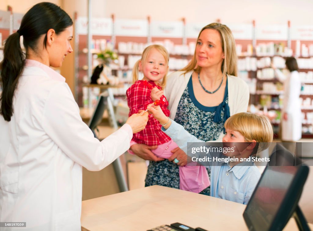 Pharmacist giving boy lollipop in store