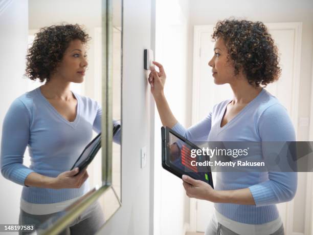 woman checking thermostat with energy tracking application on digital tablet - lowering stockfoto's en -beelden