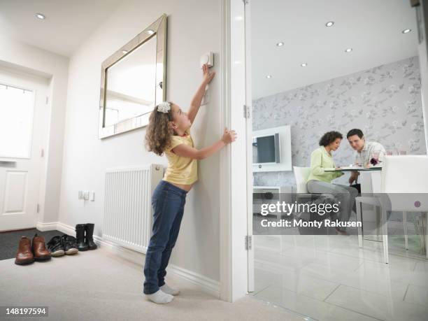 girl adjusting thermostat in energy efficient house as parents sit in the living room - child raised arms age 3 stock pictures, royalty-free photos & images