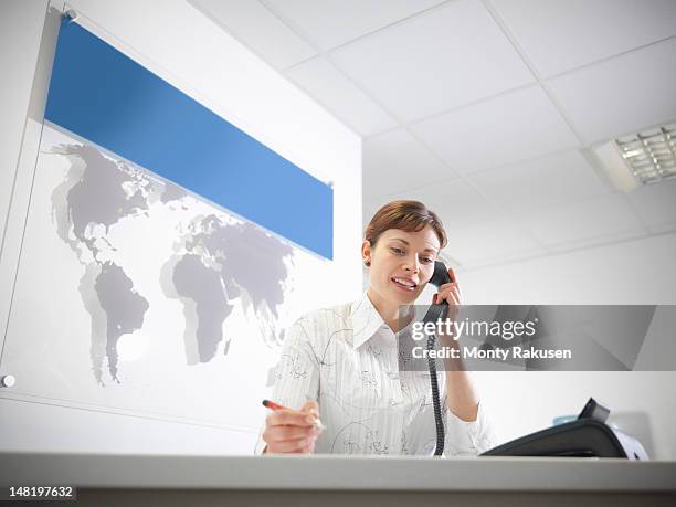 dental receptionist taking telephone call at reception desk - travel agent stock pictures, royalty-free photos & images