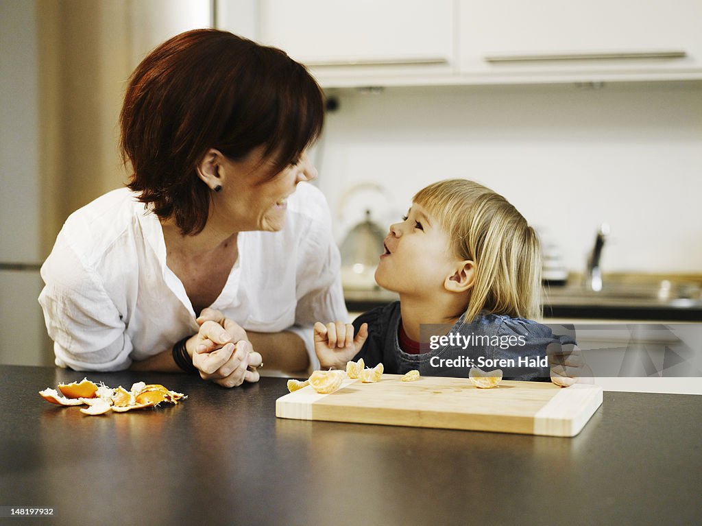 Mother and daughter peeling orange
