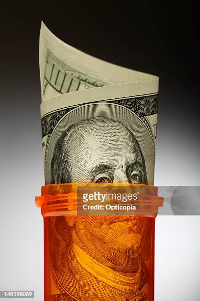 close up of u.s. dollars in pill bottle - prescription drug costs stock pictures, royalty-free photos & images