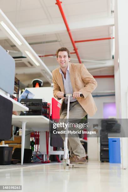 businessman riding scooter in office - ohne zusammenhang stock-fotos und bilder