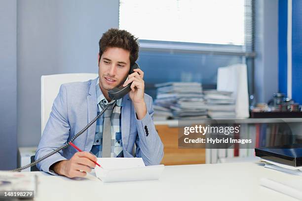 businessman talking on phone at desk - festnetztelefon stock-fotos und bilder