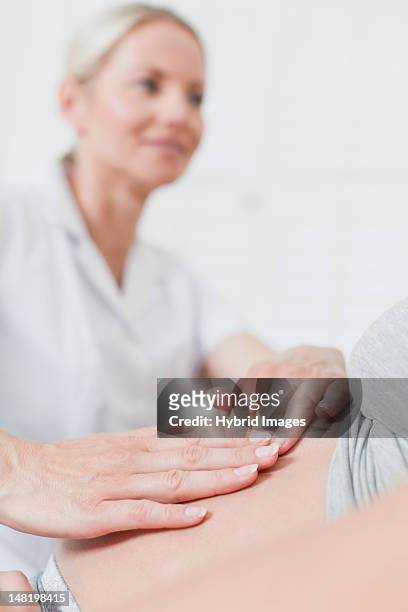doctor examining pregnant womans belly - mid wife stock pictures, royalty-free photos & images