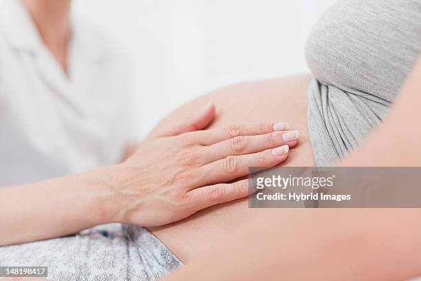 doctor examining pregnant womans belly - midwifery stock-fotos und bilder