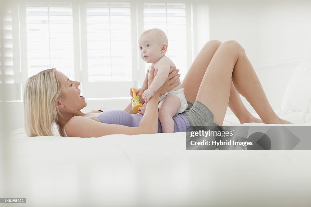 Mother playing with baby on bed