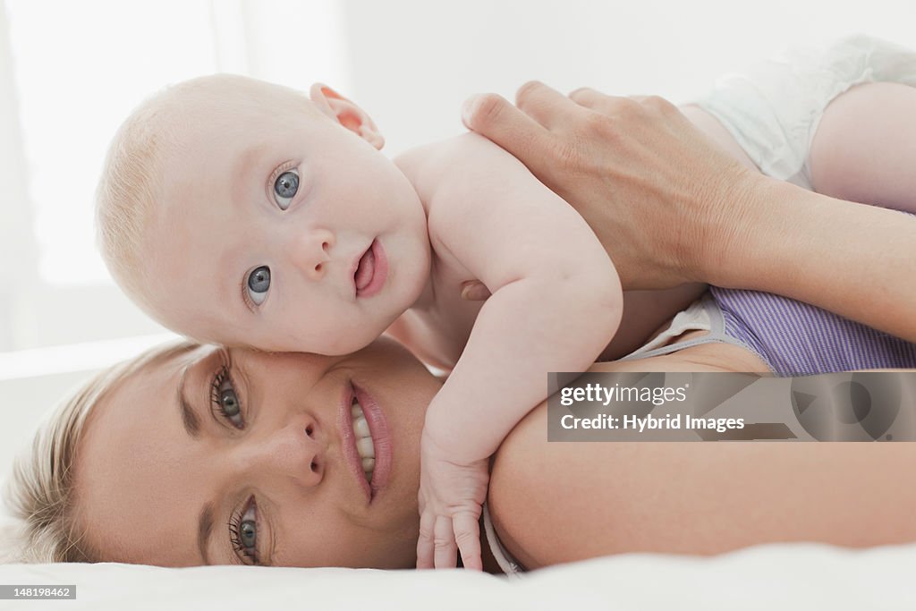 Mother hugging baby on bed