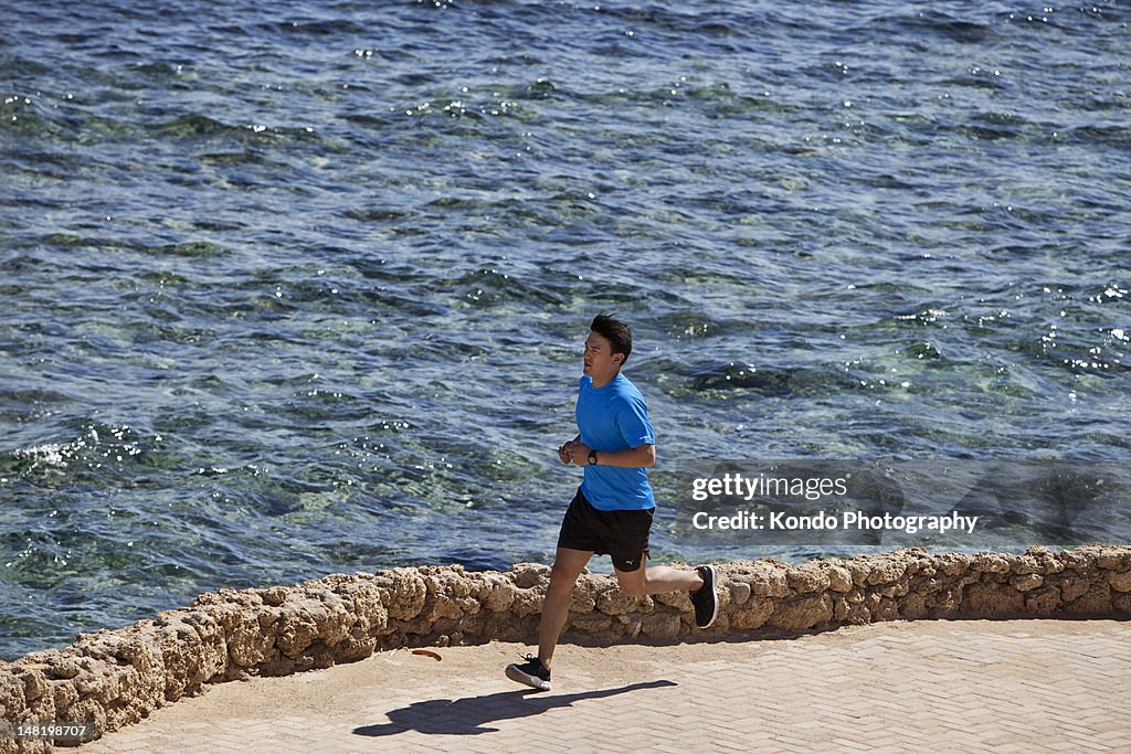 Man running on paved coastline