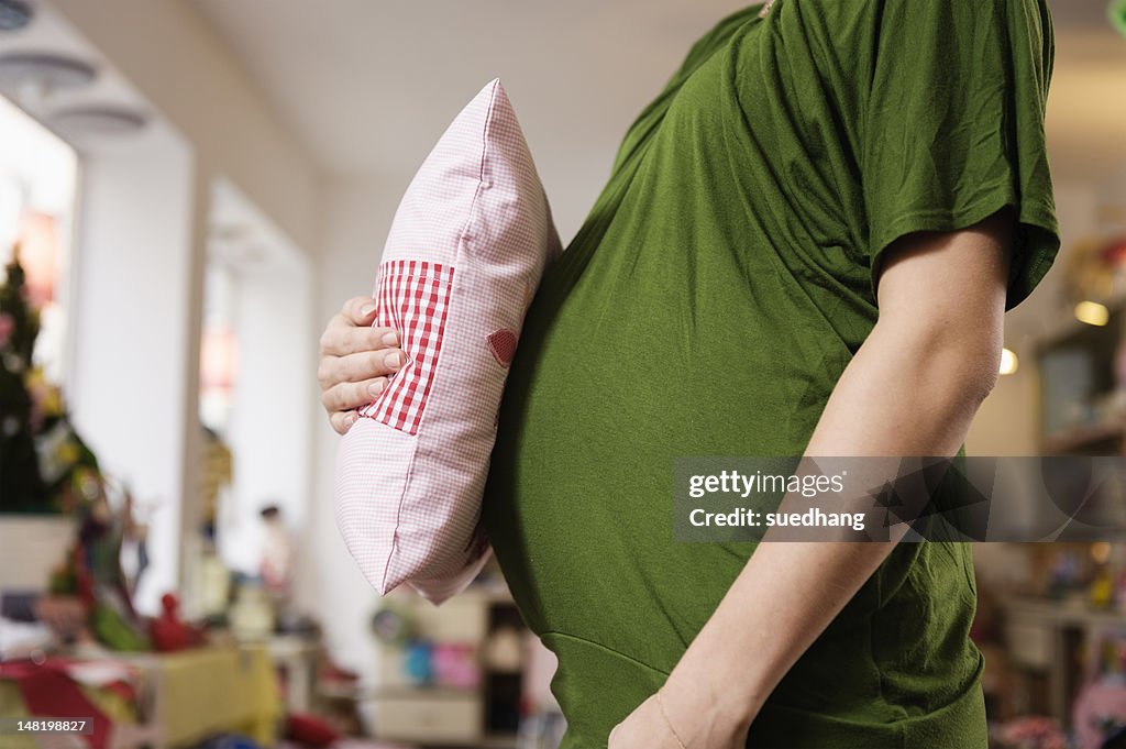 Pregnant woman holding pillow to belly