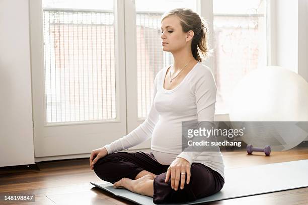 pregnant woman practicing yoga on mat - prenatal care stock pictures, royalty-free photos & images