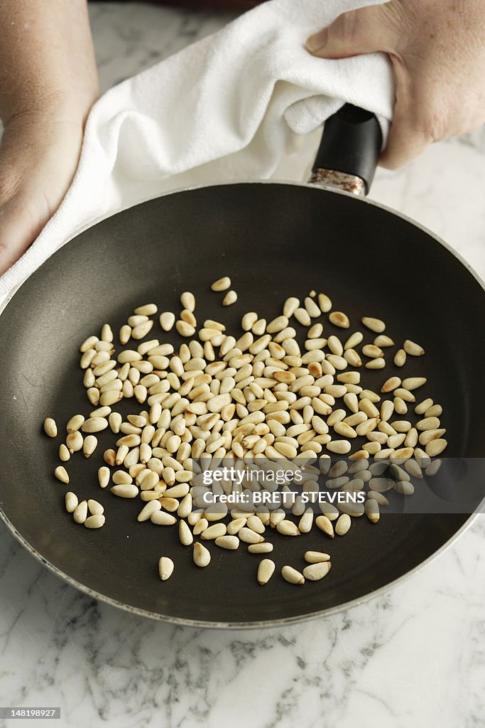 Chef toasting pine nuts in pan