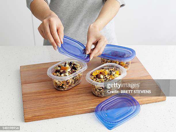 woman packing granola in tupperware - bandeja fotografías e imágenes de stock