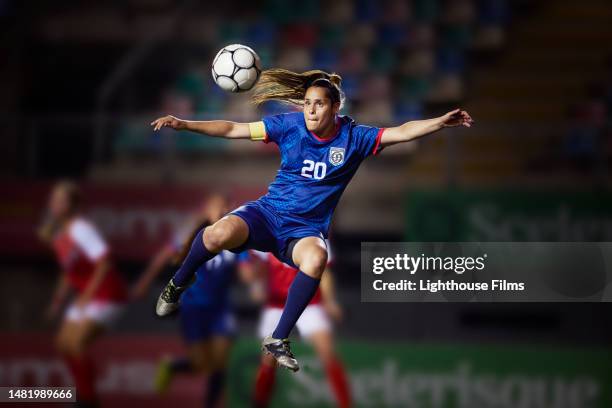 professional female soccer player focuses on the soccer ball in preparation to strike it into the goal - mid adult - fotografias e filmes do acervo