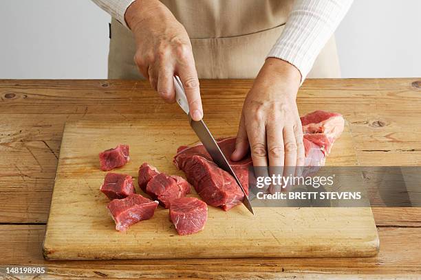 woman slicing meat on wooden board - meat stock pictures, royalty-free photos & images