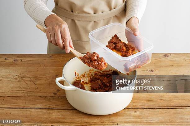 woman spooning meat into tupperware - leftovers 個照片及圖片檔