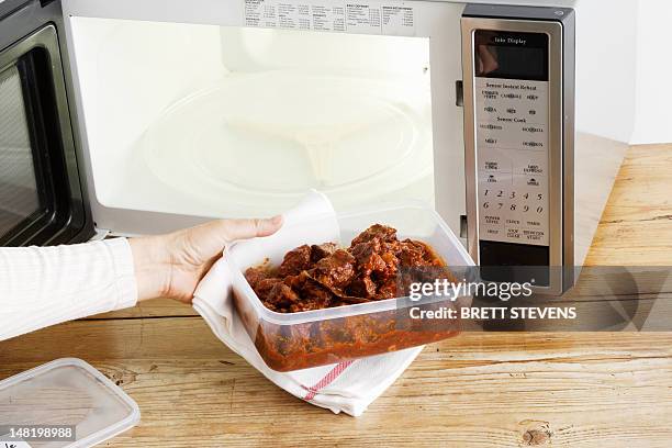 woman heating leftovers in microwave - mikrowelle stock-fotos und bilder