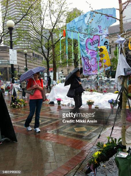 View of people with umbrellas as they walk through a memorial for the victims of the Boston Marathon Bombing , Copley Square, Boston, Massachusetts,...