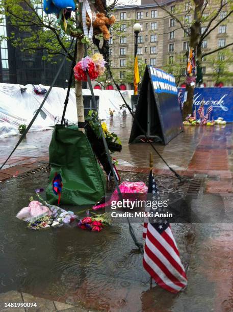 Close-up of flowers and American flag, among other items, on and around a tree at a memorial for the victims of the Boston Marathon Bombing , Copley...