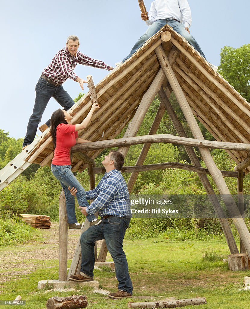 People building log hut together