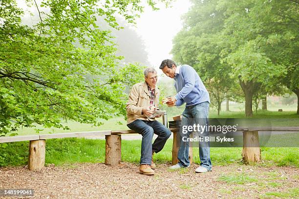 men talking in park - chatting park stockfoto's en -beelden