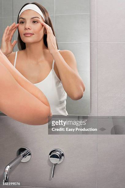 woman examining her face in mirror - tap forehead stock pictures, royalty-free photos & images