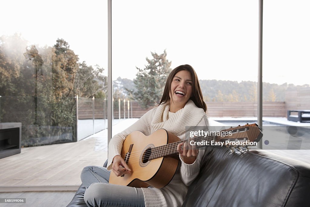 Woman playing guitar in living room