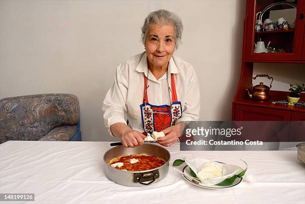older woman slicing cheese for pizza - italie stockfoto's en -beelden