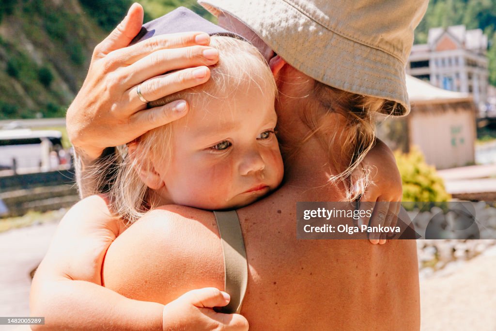 Woman hugs and soothes a crying baby on the beach