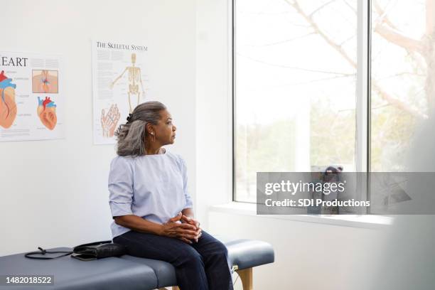 mature woman sits on the examination table and waits for the doctor - examination table stock pictures, royalty-free photos & images