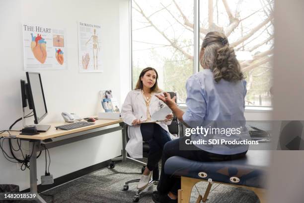 female doctor sits down to listen to her patient describe some issues she is concerned with - cardiologist stock pictures, royalty-free photos & images