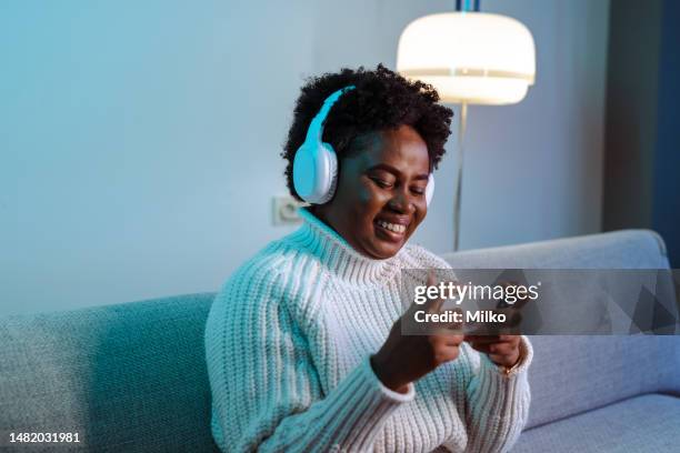 young african american woman watching online content on smart phone - mobile game stock pictures, royalty-free photos & images