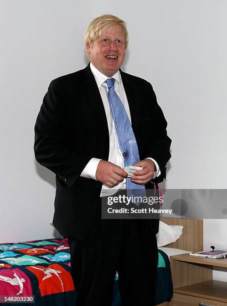 Mayor of London Boris Johnson picks up a packet of Olympic branded condoms during a visit to the Olympic Park and Olympic Village on July 12, 2012 in...