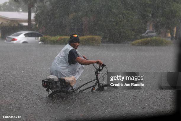 Person walks his bike through a flooded street on April 13, 2023 in Fort Lauderdale, Florida. Nearly 26 inches of rain fell on Fort Lauderdale over a...