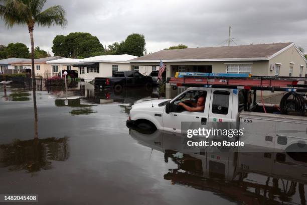 Person sits in a stalled truck along a flooded street on April 13, 2023 in Fort Lauderdale, Florida. Nearly 26 inches of rain fell on Fort Lauderdale...