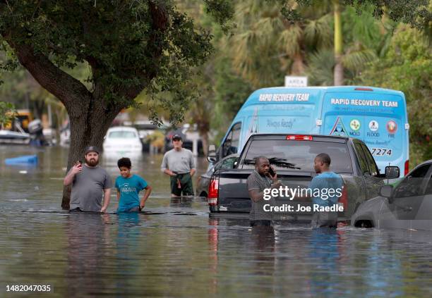People walk through a flooded neighborhood on April 13, 2023 in Fort Lauderdale, Florida. Nearly 26 inches of rain fell on Fort Lauderdale over a...